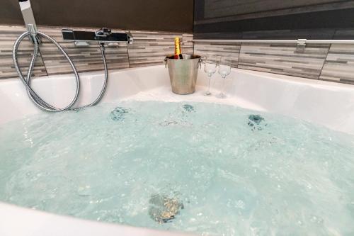 una bañera con dos copas de vino. en The Cliff Appartament Suite, en Aci Castello