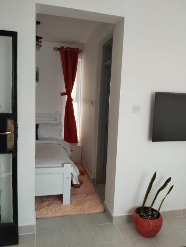 a bedroom with a bed and a window with a red curtain at Sunstone Studio- Ngong Rd Near Junction Mall in Nairobi