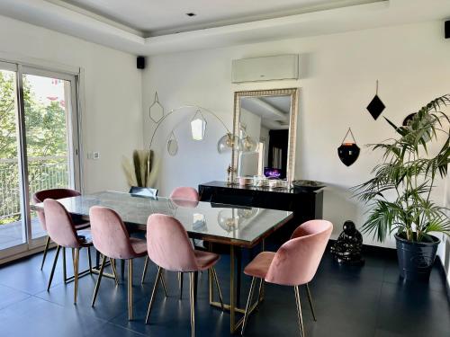 une salle à manger avec une table en verre et des chaises roses dans l'établissement Appart Prado proche vélodrome proche vieux port, à Marseille