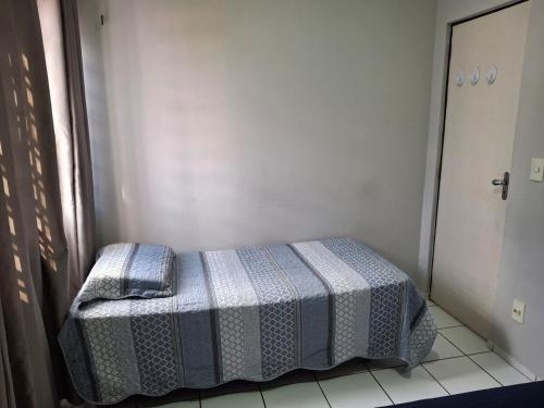 a small bedroom with a bed with a checked blanket at Apartamento aconchegante e completo in Teresina