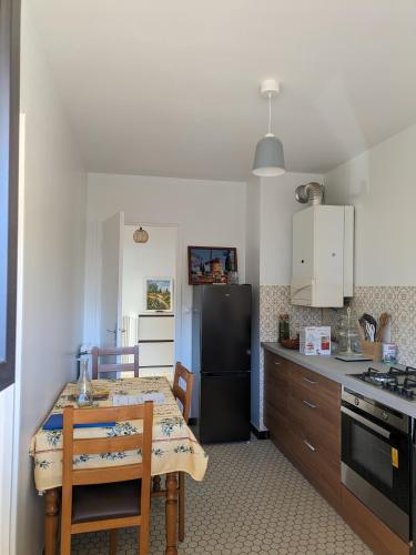 Il comprend une cuisine équipée d'une table et d'un réfrigérateur noir. dans l'établissement Appartement spacieux et calme, à Saint-Raphaël