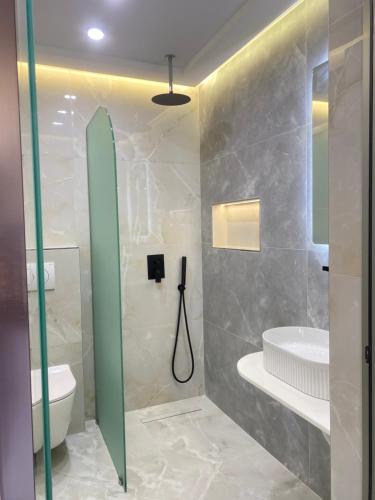 a bathroom with a shower and a sink and a toilet at Hotel Mesun Himare in Himare