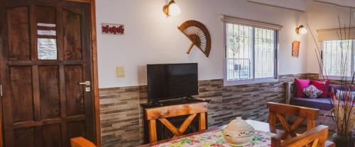 ein Wohnzimmer mit einem TV und einem Tisch mit einem sidx sidx in der Unterkunft Cabaña Morada del Cerro - Cabaña Chañar - in Capilla del Monte