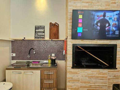 a kitchen with a tv on a wall with a fireplace at Casa 3 Quartos 5 min Centro 15 min aeroporto in Foz do Iguaçu