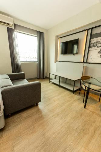 a living room with a couch and a table and a tv at Royal Golden Hotel - Savassi in Belo Horizonte