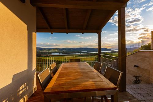 a wooden table and chairs on a balcony with a view at Fülemüle Vendégház in Zebegény