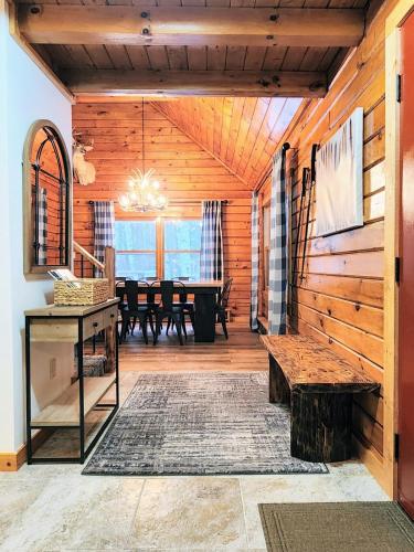 a dining room with a table and a wooden wall at Stylish Forest Lodge with Large Hot Tub, Firepit and Fireplace minutes to Gore Mountain in North Creek