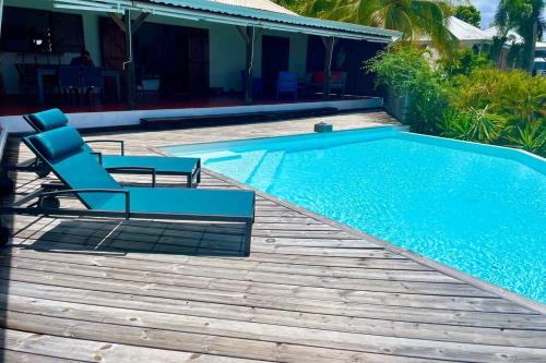 una piscina con terraza y una silla junto a ella en Villa Libellule, en Grand-Bourg
