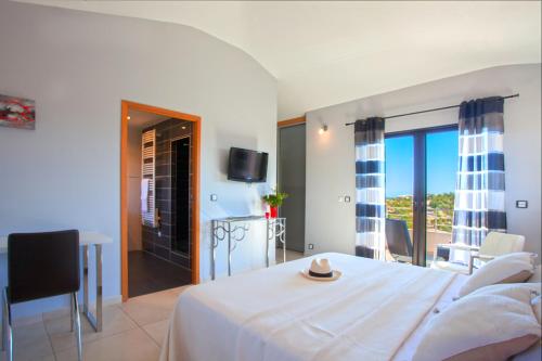 a bedroom with a white bed and a balcony at Chambres d'hôtes Casa di l'Oru in Porto-Vecchio