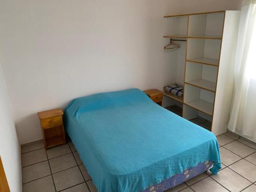 a small bedroom with a blue bed and shelves at Departamentos Ostende in Ostende