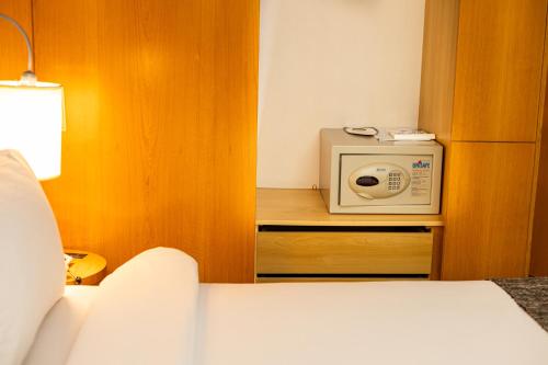 a small room with a bed and a microwave at Royal Golden Hotel - Savassi in Belo Horizonte