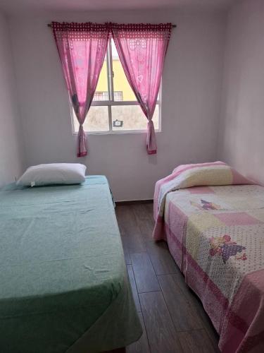 a bedroom with two beds and a window with pink curtains at Casa Fracc Paseos de la Plata Pachuca Hidalgo in Pachuca de Soto