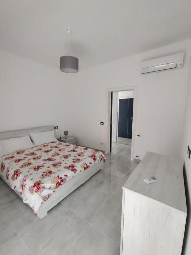a white bedroom with a bed and a table at The Blue House - Parking Space Included in Minturno