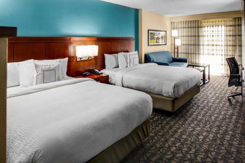 a hotel room with two beds and a chair at Courtyard by Marriott New Bern in New Bern
