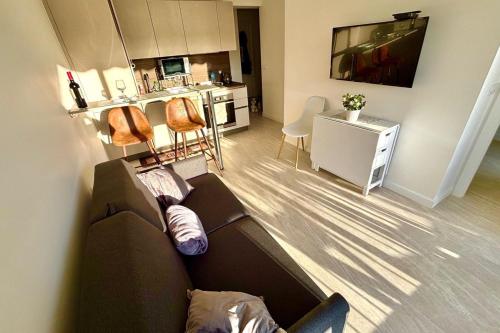 un salon avec un canapé et une cuisine dans l'établissement One-bedr ap 50m from the beach terrace swimming pool air con, à Antibes