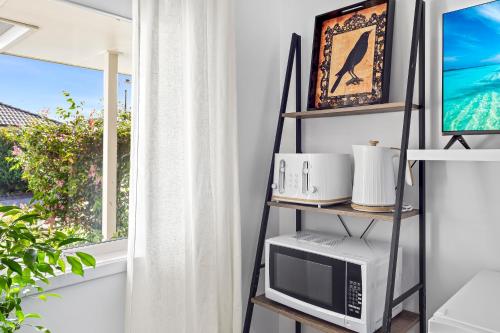 a room with a shelf with a microwave and a window at Raven Studio Griffin in Griffin