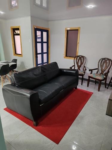 a black leather couch in a living room with a red rug at completo in San Juan