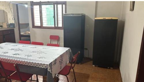 a kitchen with a table and red chairs and a refrigerator at Casa praia Guarapari in Guarapari