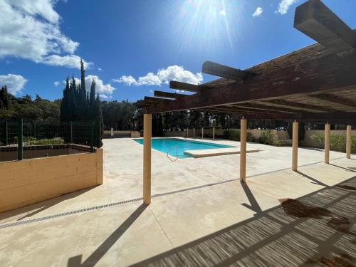 une terrasse avec une piscine et une pergola en bois dans l'établissement Appart 4pers - vue imprenable, à Fitou