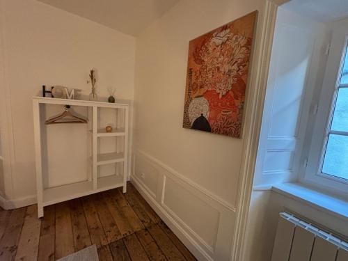 une chambre avec une étagère blanche et un tableau sur le mur dans l'établissement Charmante maison de village, à Pierrefort