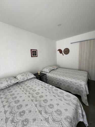 two beds in a room with white walls at Ancestral Casa de Campo in Roldanillo