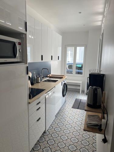 une cuisine blanche avec un évier et un micro-ondes dans l'établissement Villa à 50m de la plage, cour et parking, à Trouville-sur-Mer