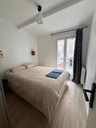 une chambre avec un grand lit et une fenêtre dans l'établissement Villa à 50m de la plage, cour et parking, à Trouville-sur-Mer