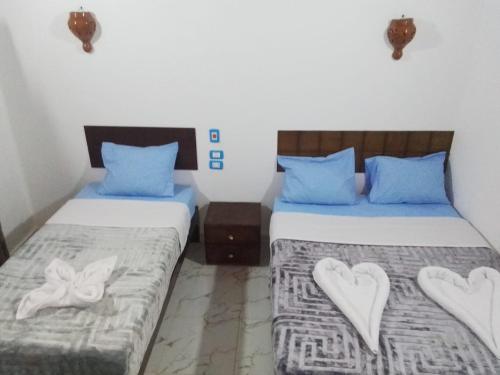 two beds in a room with blue pillows and hearts at Hannag Island in Aswan