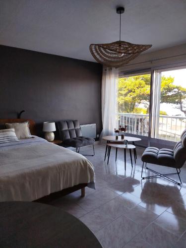 une chambre avec un lit et des chaises et une grande fenêtre dans l'établissement La Baie en direct du Balcon !, à Douarnenez