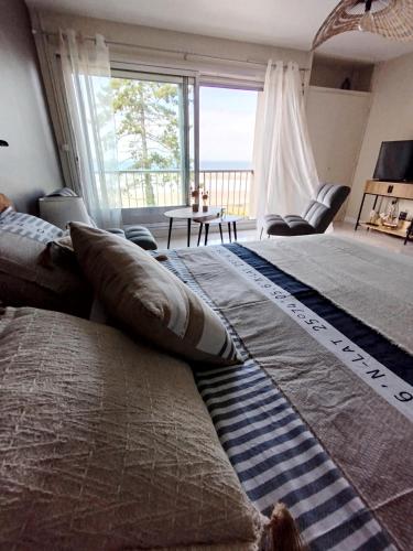 deux lits dans une chambre avec une grande fenêtre dans l'établissement La Baie en direct du Balcon !, à Douarnenez