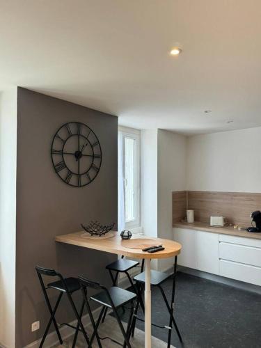 une cuisine avec une table et une horloge au mur dans l'établissement cosy spacieux appart au centre ville, à Bourg-en-Bresse