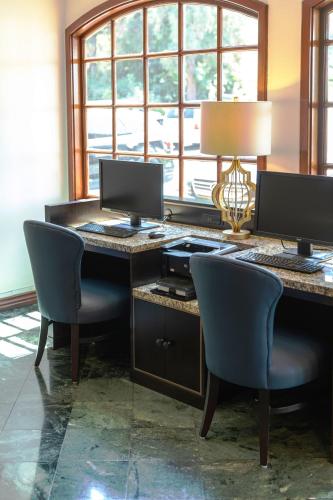 a desk with two computer monitors and two chairs at Ayres Suites Diamond Bar in Diamond Bar