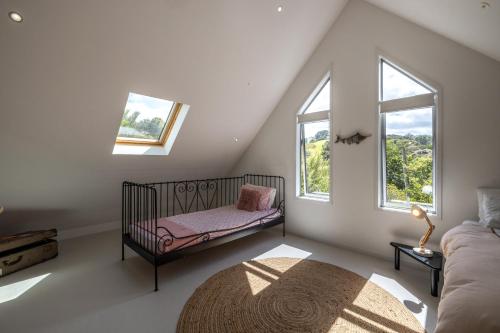 a baby crib in a room with two windows at Boathouse Onetangi - Stay Waiheke in Waiheke Island