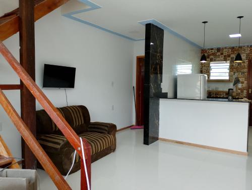 a living room with a staircase with a couch and a television at Casa de temporada em santa clara in Sao Francisco do Itabapoana