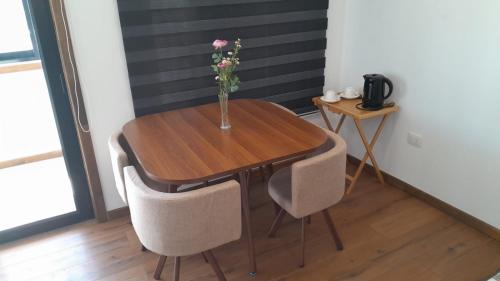 a vase of flowers on a wooden table with chairs at Departamento un ambiente centro Puchuncaví in Puchuncaví