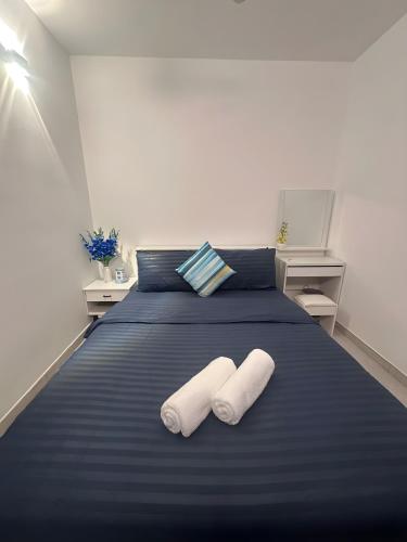 a bedroom with a blue bed with two towels on it at Lilys Homestay By Dhalhey's in Hulhumale