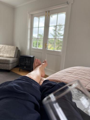 une personne assise sur un lit avec ses pieds sur le lit dans l'établissement Ohariu Farm Cottage, à Johnsonville