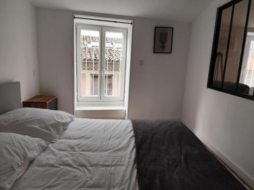 a bedroom with a white bed and a window at Le Cocon Perché in Valence