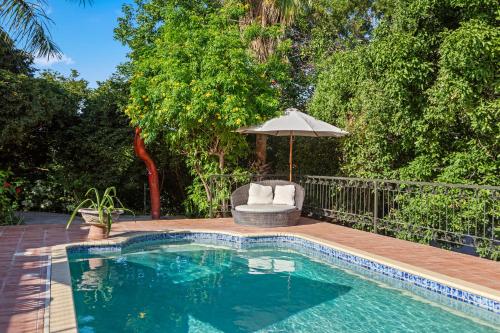 a pool with a chair and an umbrella next to a wooden deck at Villa Casablanca in Willemstad