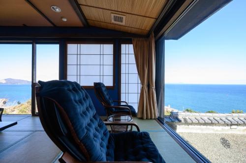 a living room with chairs and a view of the ocean at 絶景海風癒し庵 新八屋 in Toba