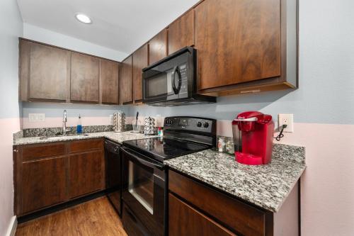 a kitchen with wooden cabinets and a red appliance at Chic & Cozy 1BR Apt with Free Parking & King Bed in Houston