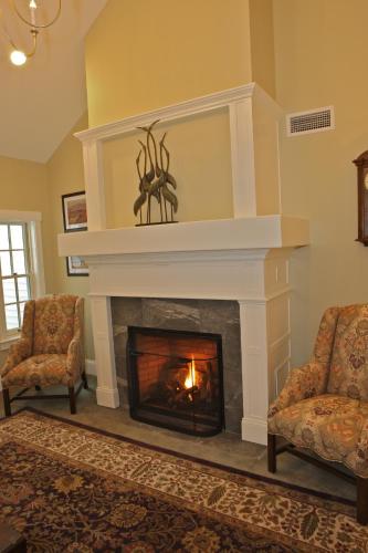 a living room with a fireplace with two chairs at Publick House Historic Inn and Country Motor Lodge in Sturbridge