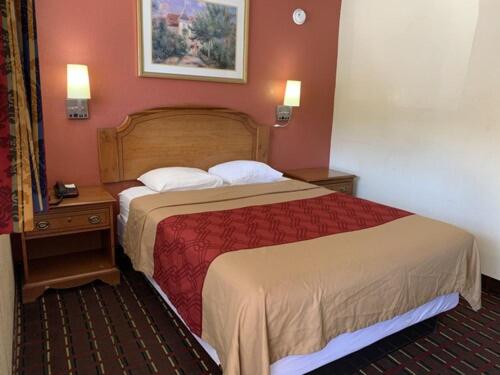 a hotel room with a bed and a night stand with a bed at Budget Inn Madill in Madill