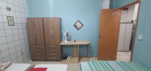a room with a table and cabinets and a room with a bed at Quarto com cozinha funcional in Guarapari