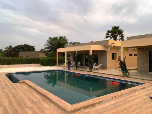 a person standing in front of a house with a swimming pool at Résidence Kanissa in Cap Skirring