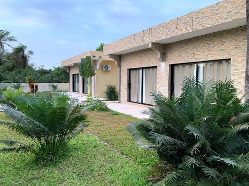 a brick house with palm trees in front of it at Résidence Kanissa in Cap Skirring
