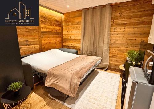 une chambre avec un lit dans une pièce aux murs en bois dans l'établissement Ski in Ski out - Plein Centre - La Clusaz, à La Clusaz