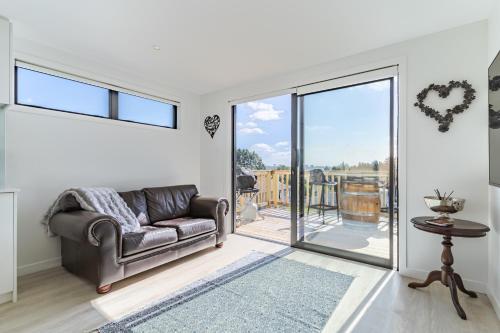 a living room with a couch and a sliding glass door at Nautilus self-catering cottage in Maraetai