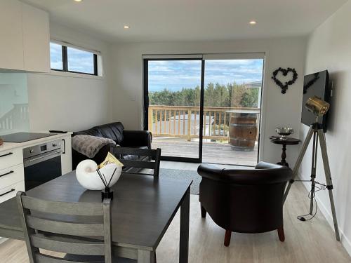 a living room with a table and chairs and a kitchen at Nautilus self-catering cottage in Maraetai