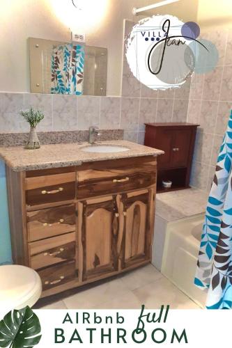 a bathroom with a sink and a mirror and a tub at Charming Villa in Ocho Rios in Ocho Rios